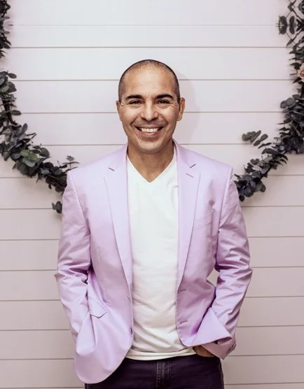 Al Fuentes, smiling, in a lavender blazer and white T-shirt